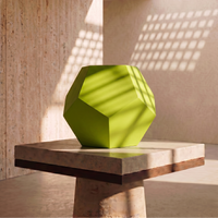 Green geometric vase on a stone surface with a modern architectural background